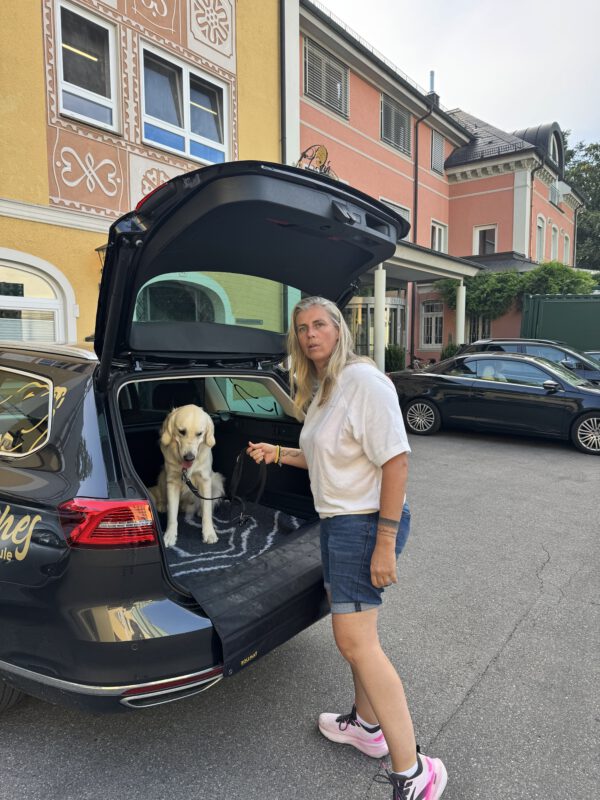 Hundepension DogBones: Evelien Smit sichert einen Gast-Hund im Kofferraum für Ausflüge und sicheren Transport während der Hundebetreuung.