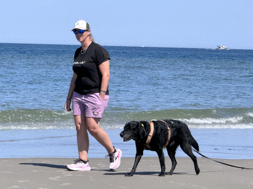 Urlaub mit Hund auf Terschelling: Evelien Smit spaziert mit ihrem schwarzen Labrador entspannt am Nordseestrand entlang.